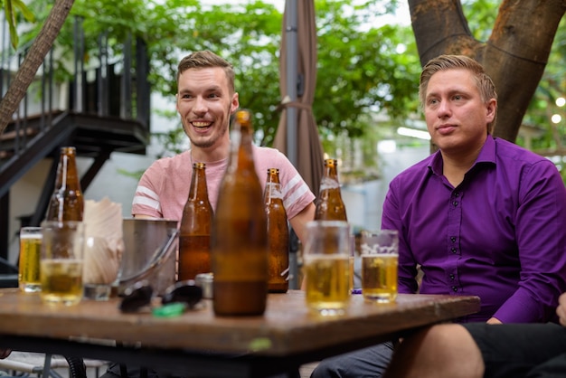 Hombres hablando y riendo mientras beben cerveza al aire libre