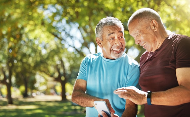 Hombres hablando y un teléfono en un parque para obtener resultados de entrenamiento físico y conversación sobre una aplicación Comunicación feliz y amigos mayores con un teléfono móvil para controlar la salud después de hacer ejercicio o correr