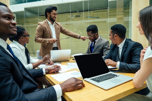 Hombres indios de negocios bien vestidos haciendo un informe a los empleados subordinados en una oficina moderna