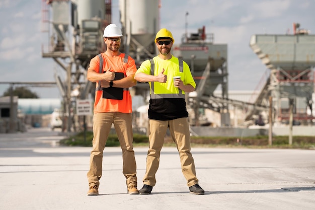 Hombres ingenieros industriales con casco mientras fábrica industrial al aire libre maquinaria industrial y fábrica