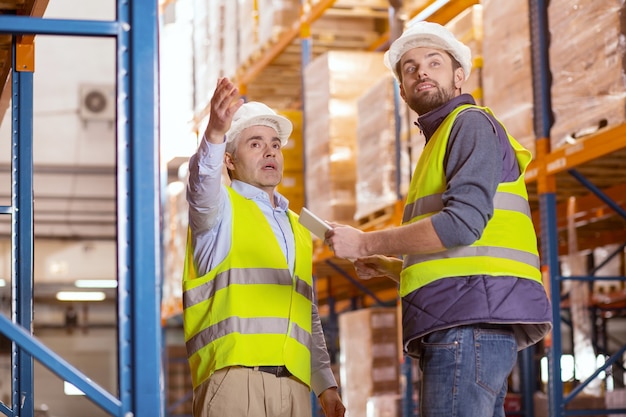 Hombres inteligentes profesionales de pie juntos mientras se discuten los problemas laborales en el almacén