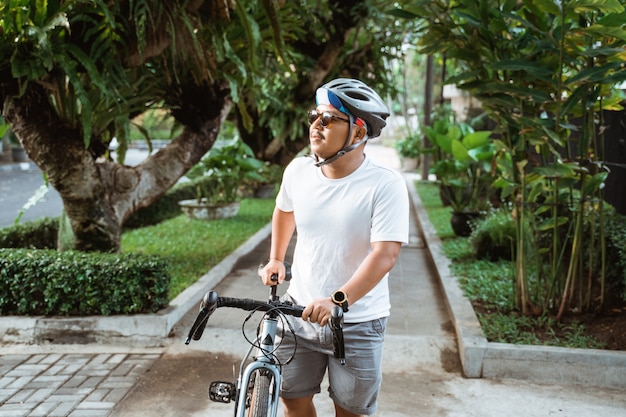 Hombres jóvenes con cascos de bicicleta caminando por bicicletas de calle