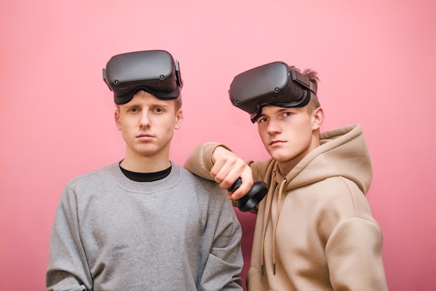 Hombres jóvenes con controlador y cascos VR jugando videojuegos