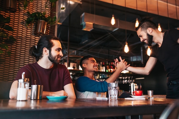 Hombres jóvenes multirraciales que se encuentran con su amigo en el bar salón