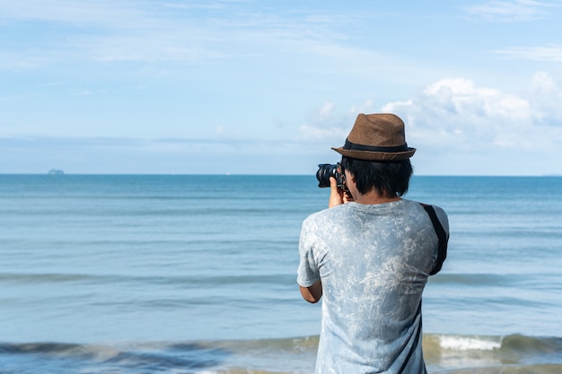 Foto los hombres jóvenes toman una foto en la playa tropical.