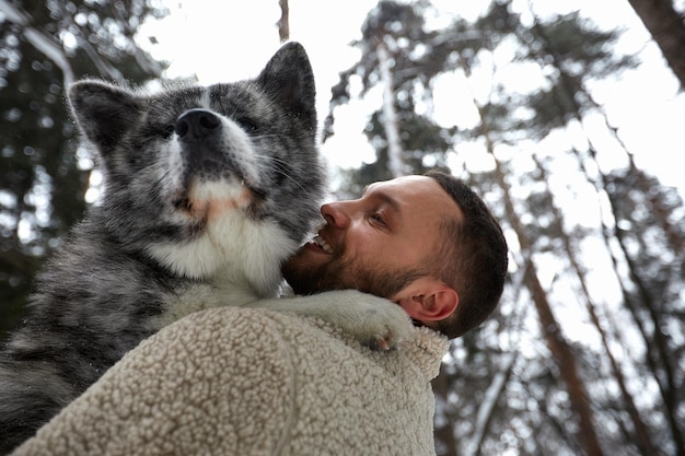 Hombres jugando con husky siberiano en el bosque de invierno y los animales del parque y la ecología Amante de las mascotas Concepto de amigo humano del perro