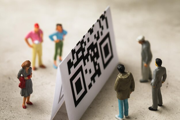 Hombres de juguete hechos de plástico y una hoja con un código de barras, el concepto de dividir a la sociedad mediante códigos QR