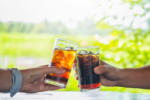 Los hombres y la mano de la mujer dando vaso de cola.