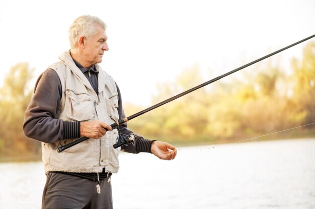 Hombres mayores pescando junto al lago.