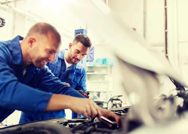 Foto hombres mecánicos con llave inglesa reparando coches en el taller