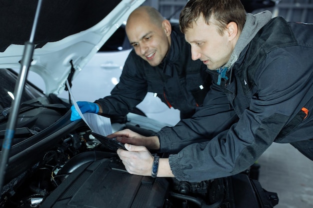Foto hombres mecánicos con llave de reparación de coches en el taller.