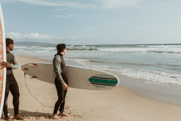 Hombres mirando a un surfista en la playa.