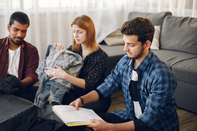 Hombres y mujeres jóvenes que se preparan para un viaje. Viajeros empacando ropa y equipaje en una maleta.