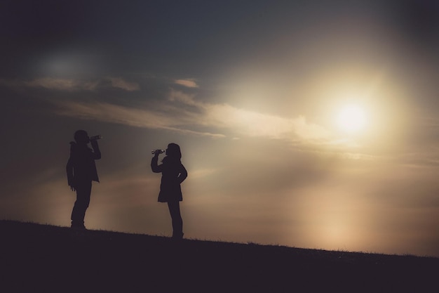 Hombres y mujeres que beben el agua en el crepúsculo de la colina