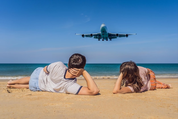 Hombres y mujeres turistas se divierten en la playa viendo los aviones aterrizando en un avión