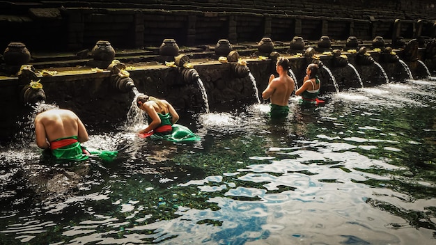 Hombres y mujeres de los turistas que hacen el ritual de la purificación en el templo de Titra Empul en Bali