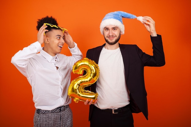 Hombres multiculturales riendo con un sombrero de Papá Noel y gafas de estrellas mirando en diferentes direcciones