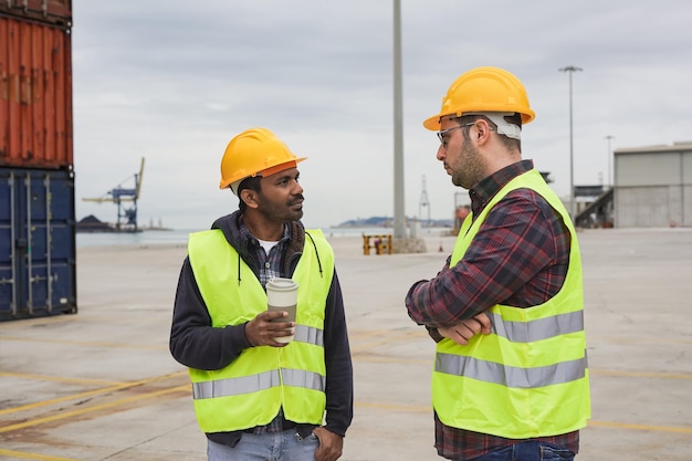 Hombres multiétnicos hablando juntos mientras están parados en un muelle comercial