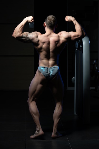 Los hombres musculosos están golpeando la postura trasera del doble bíceps
