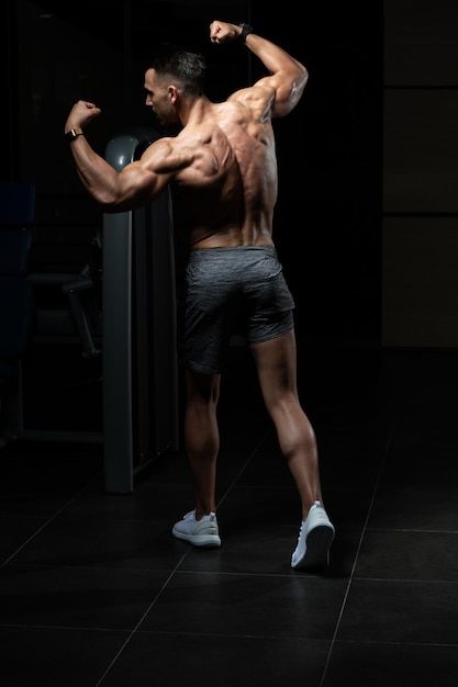 Los hombres musculosos están golpeando la postura trasera del doble bíceps