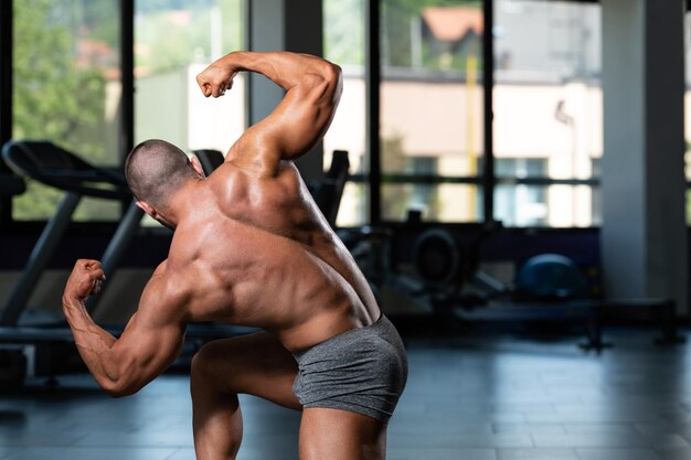 Los hombres musculosos están golpeando la postura trasera del doble bíceps