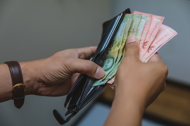 Foto los hombres de negocios abren sus billeteras con cientos de billetes de banco baht.