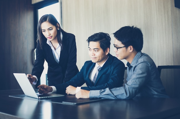 Hombres de negocios asiáticos y grupo que usa el cuaderno para discutir en la reunión