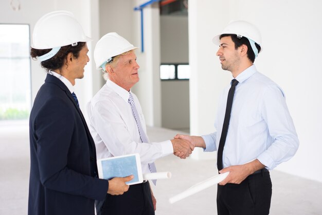 Hombres de negocios confidentes que concluyen reparto en el sitio de la construcción y sacudir las manos