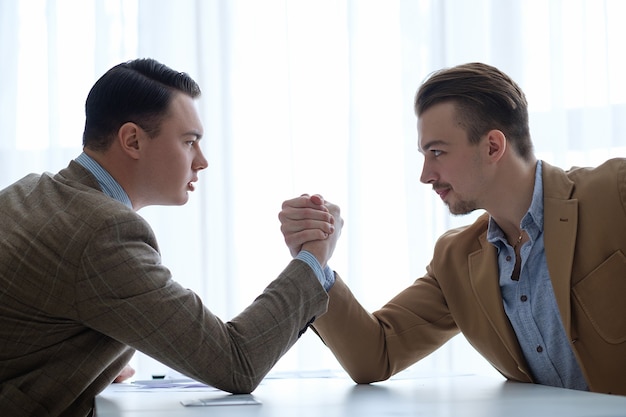 Los hombres de negocios se enfrentan y se oponen. lucha de brazos para determinar el liderazgo.