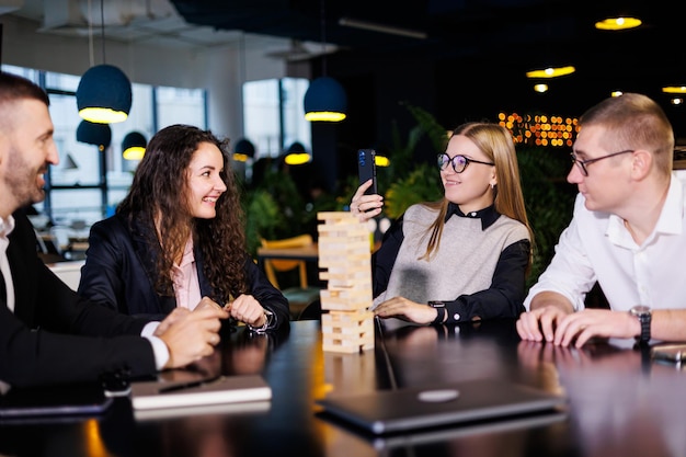 Los hombres de negocios están jugando juegos de Jenga. Se sientan en la oficina y juegan. Fotografía conceptual para el diseño y el trabajo.