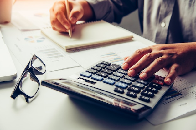 Los hombres de negocios están usando una calculadora para calcular los ingresos del negocio.