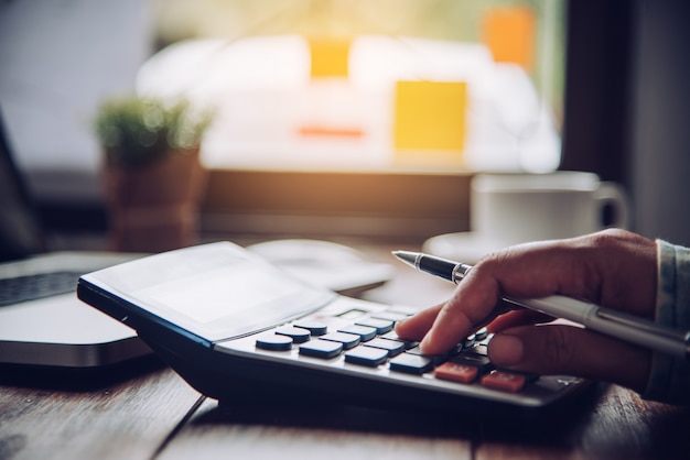 Los hombres de negocios están usando una calculadora para calcular los ingresos del negocio.