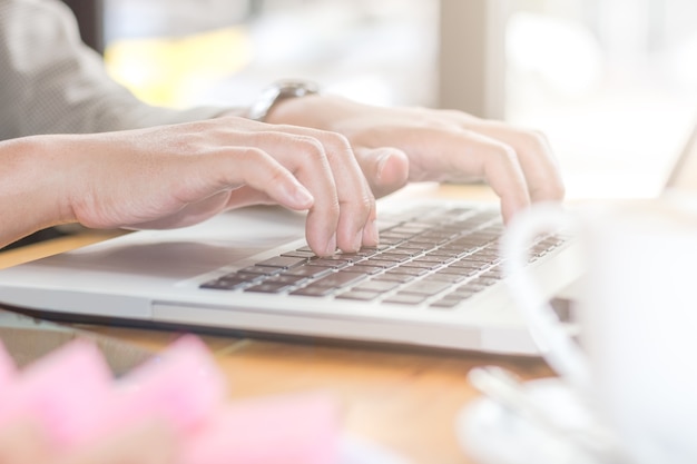 Los hombres de negocios están utilizando un teléfono inteligente y una computadora portátil en una cafetería