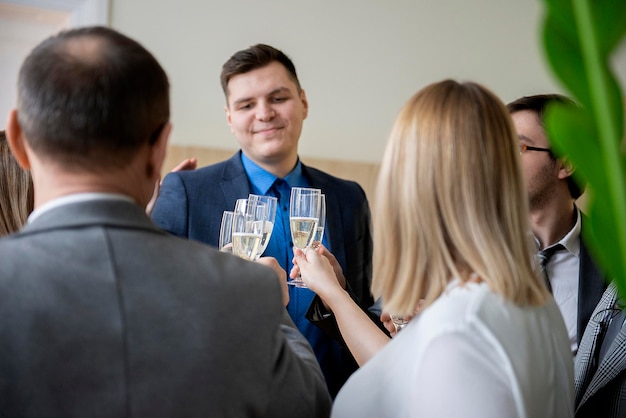 Foto los hombres de negocios exitosos están tocando copas de champán y sonriendo mientras celebran en la oficina.