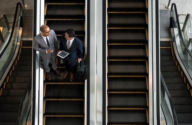 Los hombres de negocios hablan de la escalera mecánica de la tableta