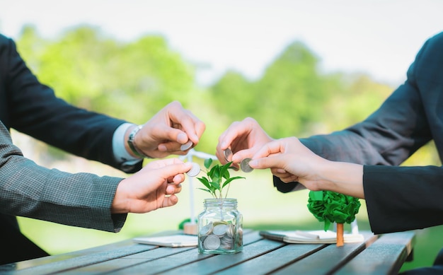 Los hombres de negocios ponen moneda a dinero ahorrando frasco de vidrio Gyre