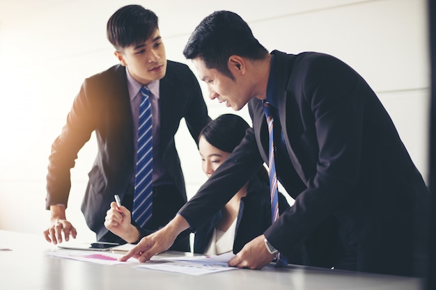 Los hombres de negocios que trabajan y apuntan en el diagrama del diagrama financiero y los documentos de análisis en la mesa de la oficina