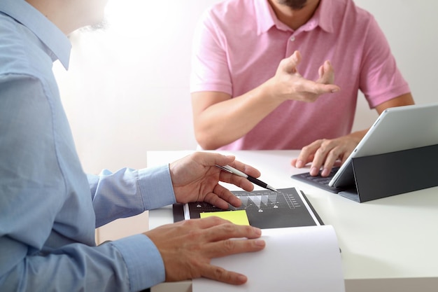 Hombres de negocios trabajando juntos en un documento y usando teléfonos inteligentes, tabletas digitales y computadoras portátiles