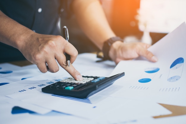 Los hombres de negocios usan la calculadora para calcular y analizar los beneficios de la compañía
