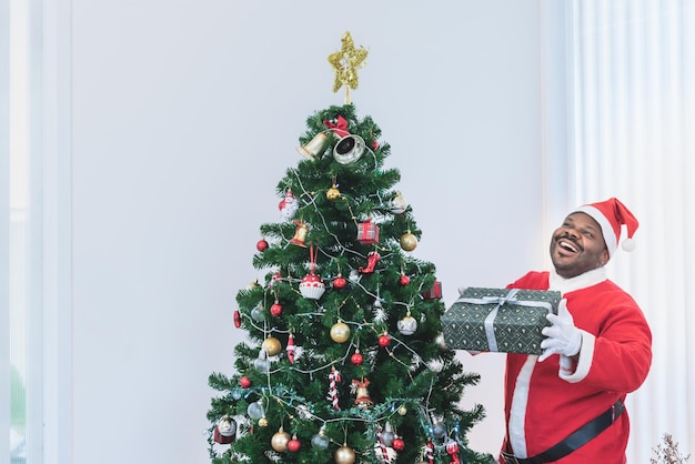 Hombres nigerianos vestidos de Papá Noel rojo sosteniendo muchas cajas de regalo con luces de árboles de Navidad