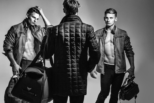 Los hombres o el fotógrafo con el torso desnudo y el cuerpo sexy sostiene una cámara de fotos y bolsas en blanco y negro