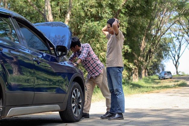 Hombres parados cerca del automóvil con el capó levantado que tienen problemas con su vehículo Falla del automóvil mientras o