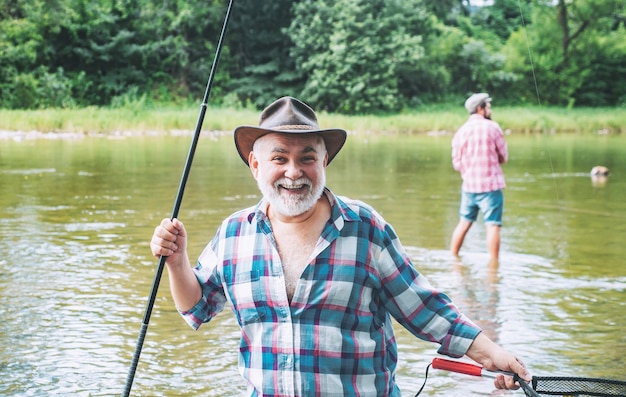 Hombres pescando en el río durante el día de verano pescador feliz pescando en el río sosteniendo cañas de pescar truchas o