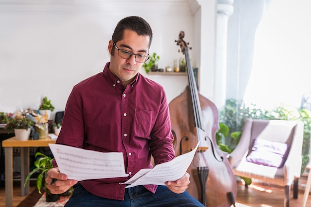 Los hombres que leen partituras en casa se centran en la partitura y en sus manos