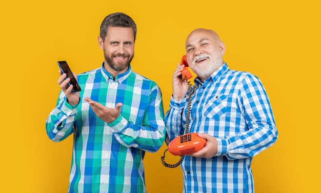 Hombres que presentan producto de llamada telefónica de contraste aislado en amarillo