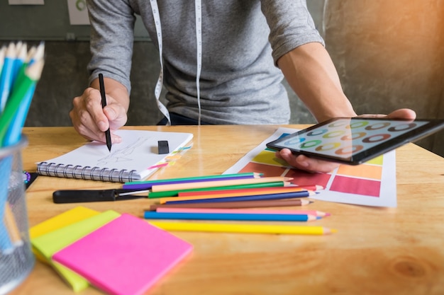 hombres que trabajan como diseñador de moda que eligen en la carta de color para la ropa en tableta digital en el estudio del lugar de trabajo.