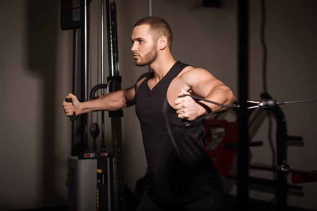 Hombres sexy deportivos con grandes músculos abdominales en ropa deportiva negra haciendo ejercicio en el gimnasio.