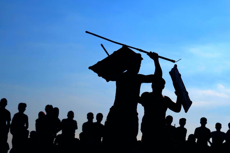 Foto hombres siluetas luchando frente a la multitud contra el cielo azul
