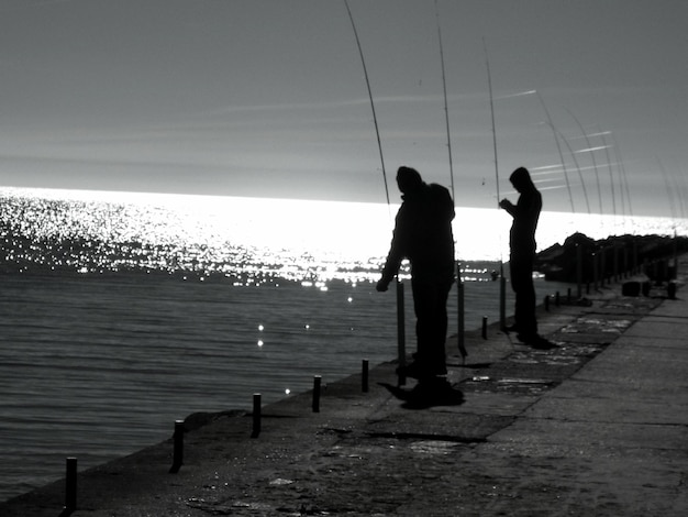 Foto hombres siluetas pescando en el lago contra el cielo