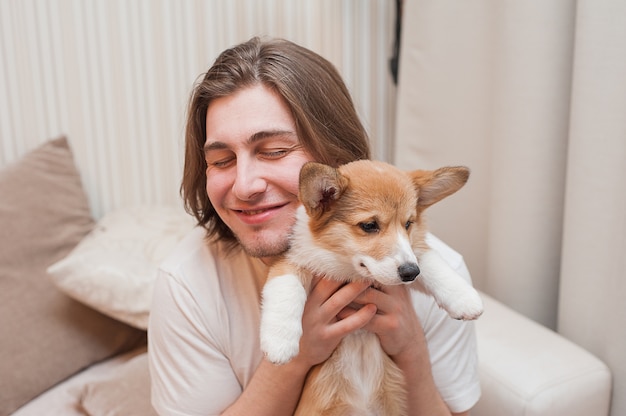 Hombres sonrientes felices se abrazan a sí mismos con un cachorro Corgi.